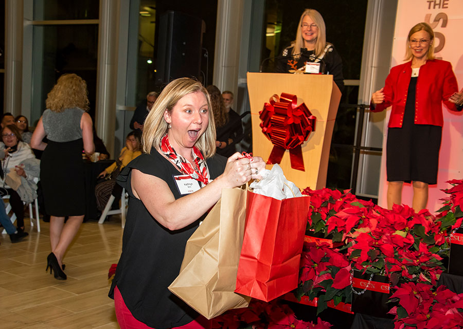 National Center on Deafness interpreter Kathryn Bess celebrates as she picks up a prize from the Winter Celebration raffle.