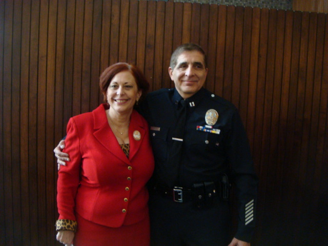 Chris Zingo in red suit, pictured with her late husband Nick Zingo in his Los Angeles Police Department uniform.