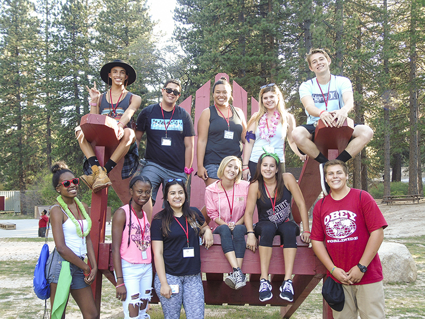 Students sit on an oversized red chair and pose for a group photo at Ponderosa Pines Camp.