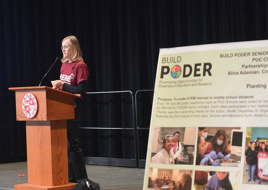 Carrie Saetermoe, standing by a BUILD PODER poster