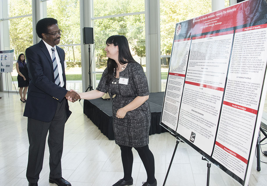 Vice President for Student Affairs and Dean of Students William Watkins shakes hands with Presidential Scholar Natalie Rankin by her research poster.