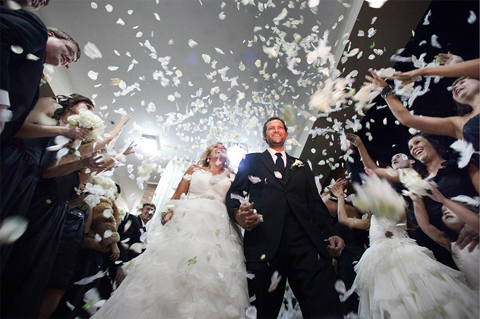 Newlyweds are showered in flower pedals by friends and family in a dramatic photo from Joe Buissink.