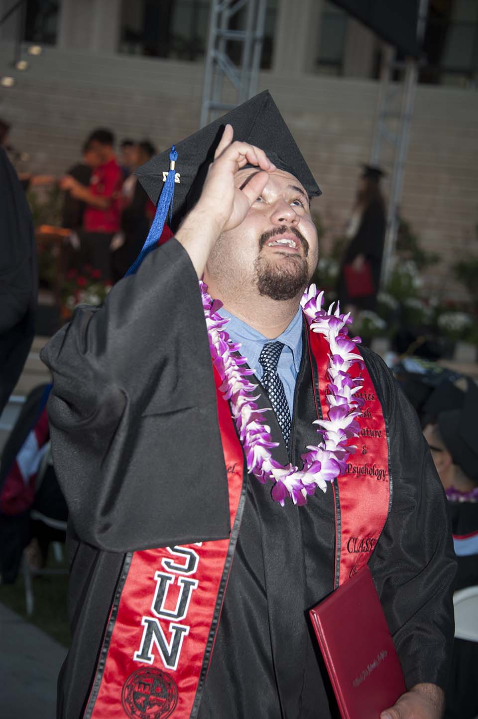 A CSUN graduate points to the sky during 2017 commencement.