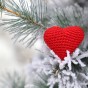 Red knit heart nestled in snowy branches