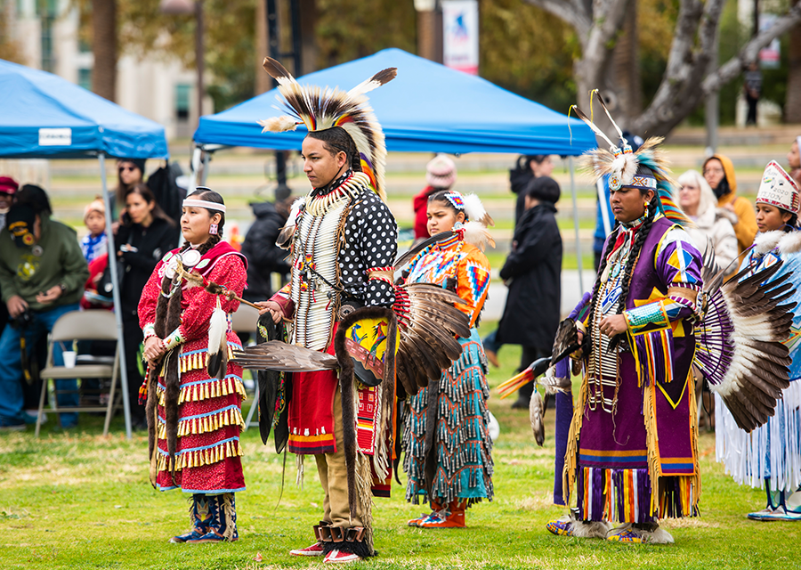 A line of people in American Indian regalia at the 2019 CSUN Powwow.