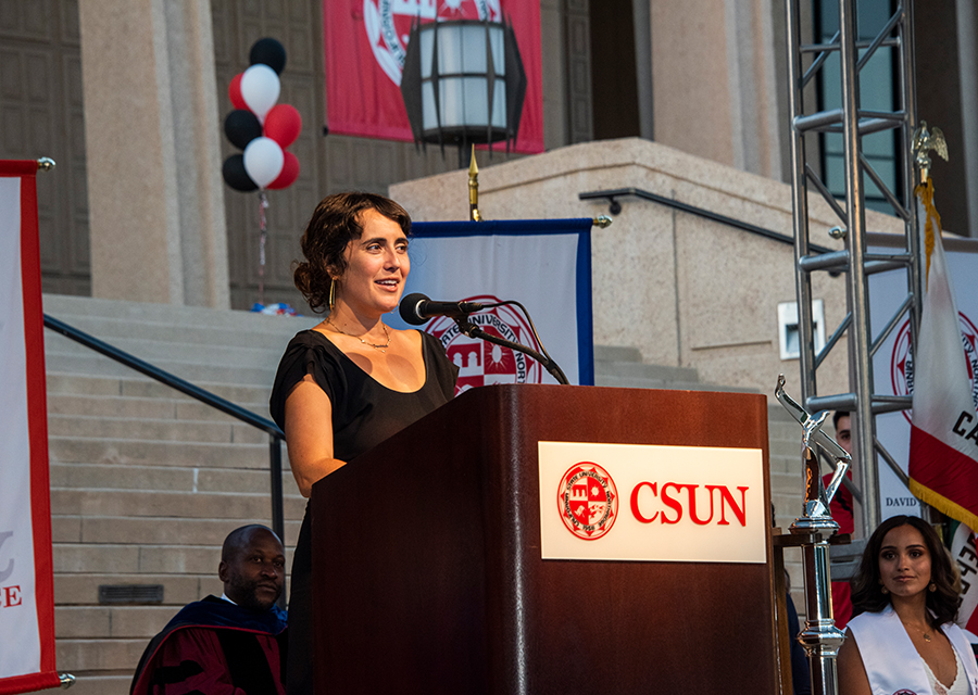 Lauren Markham speaks at a CSUN podium in front of the library.