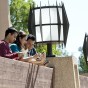 Three students are engaged in their tablets outside of the Oviatt Library.