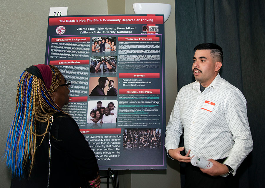 Valente Soria explains the poster he put together with Tieler Howard and Dorna Mirzad to an attendee.