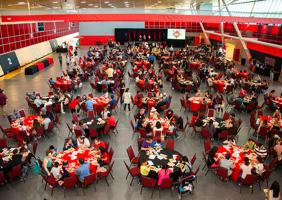 An over head shot of hundreds of tables are set up with a handful of people at each.