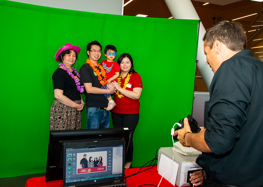 A family stands in front of a green screen, waiting for their photo to be taken.