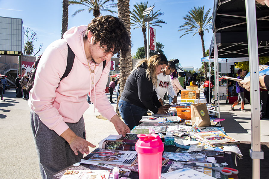 Students crowd over a table covered in magazine clippings to participate in arts and crafts.