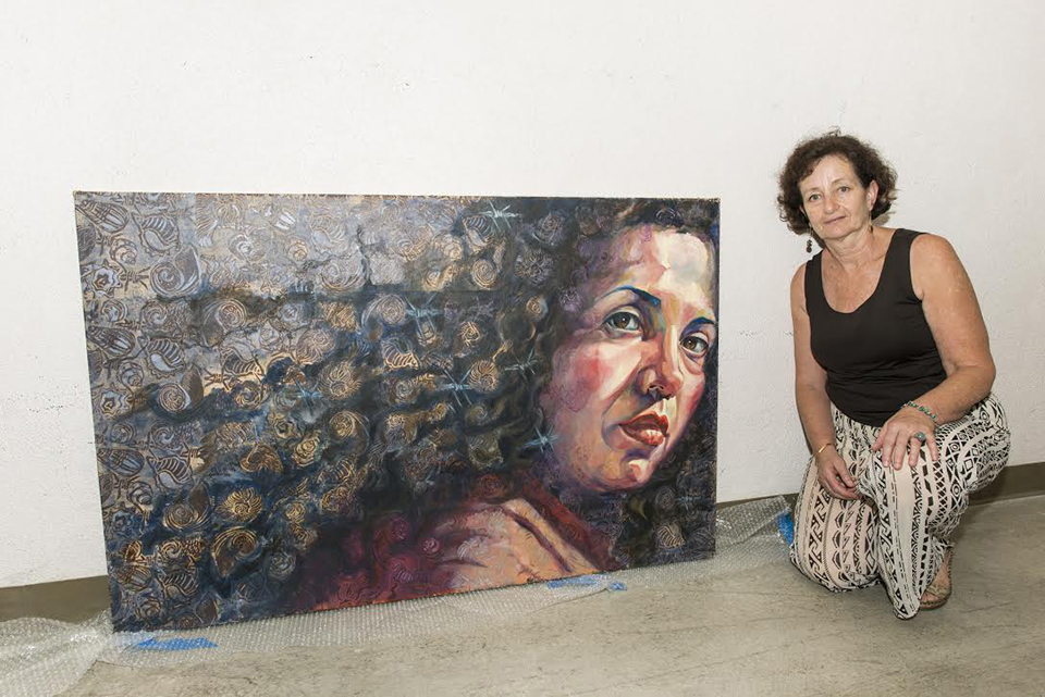 CSUN art student Nurit Avesar stands with her painting for the University Student Union. The piece tells a story about a friend who traveled through El Salvador. Photo by David J. Hawkins.